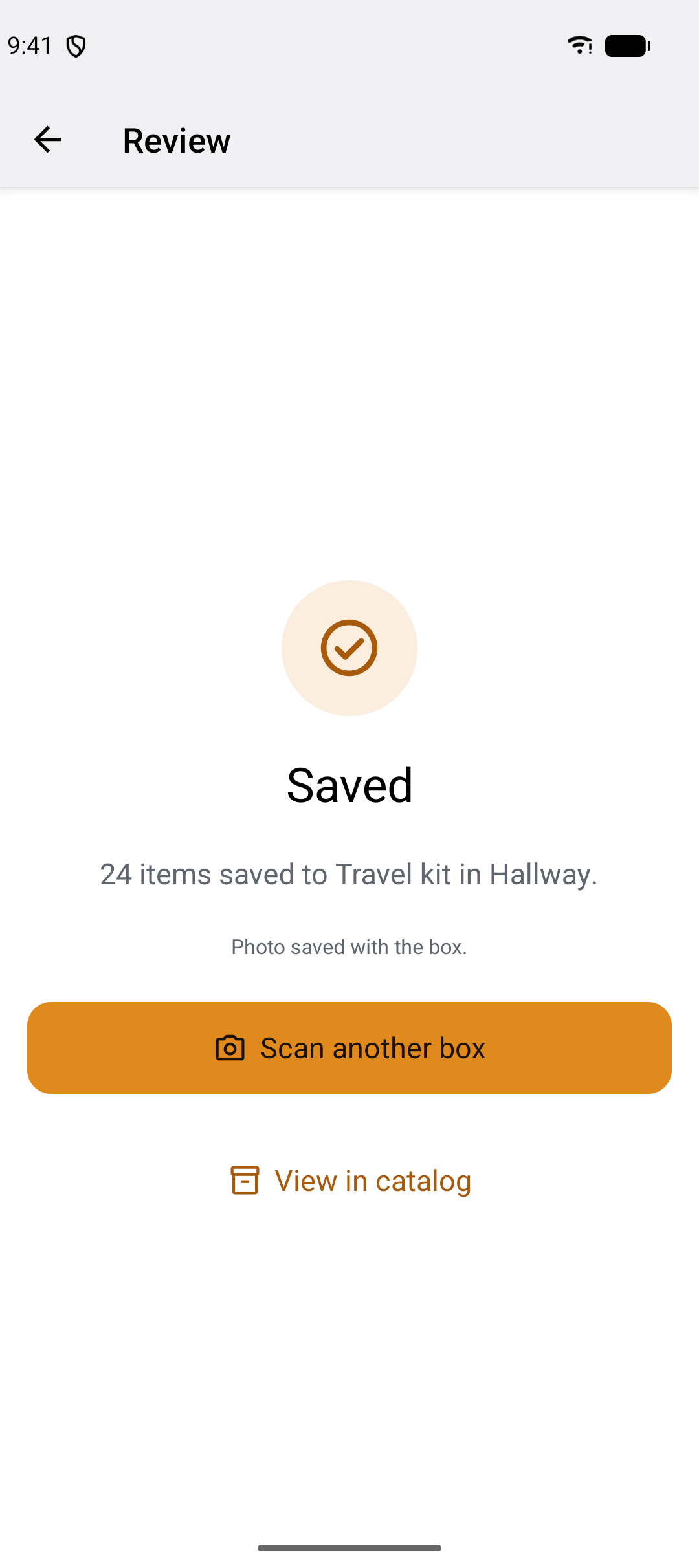 The confirmation screen: a marigold tick, the word Saved, the line 24 items saved to Travel kit in Hallway, and the buttons Scan another box and View in catalog.