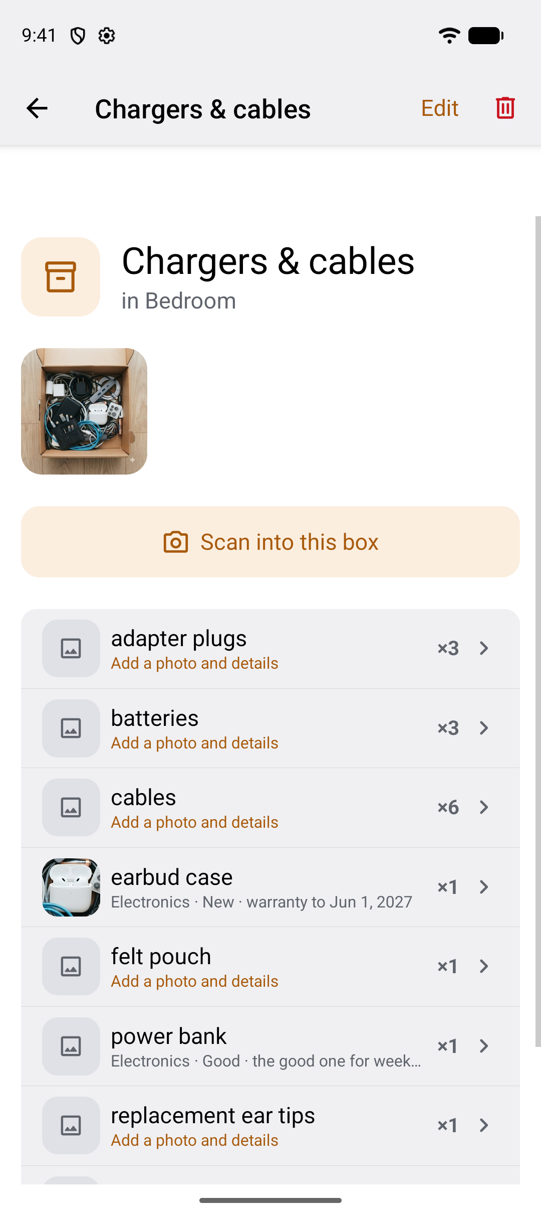 A spot screen: Chargers and cables, in Bedroom, with the photo of the open spot, a Scan into this box button, and item rows — adapter plugs times 3, batteries times 3, cables times 6, earbud case with the detail Electronics, New, warranty to 1 June 2027.