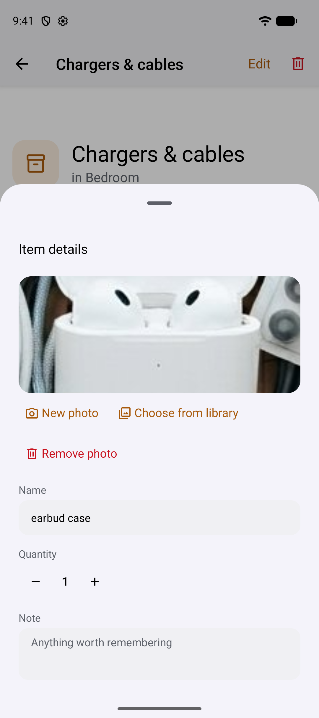 The item details sheet over the spot screen: a photo of an earbud case, the actions New photo, Choose from library and Remove photo, a name field reading earbud case, a quantity stepper set to 1, and a note field.